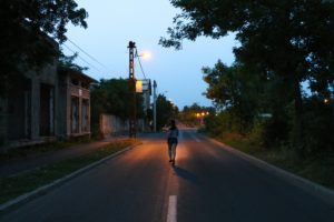 夜の田舎道をジョギングする女性